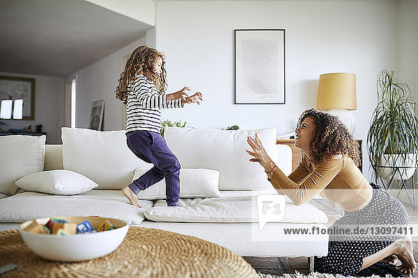 Side view of happy mother playing with daughter in living room