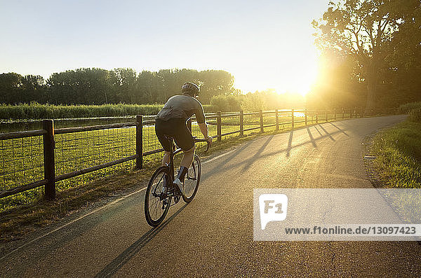 Männlicher Athlet fährt bei Sonnenschein auf Straße und Feld