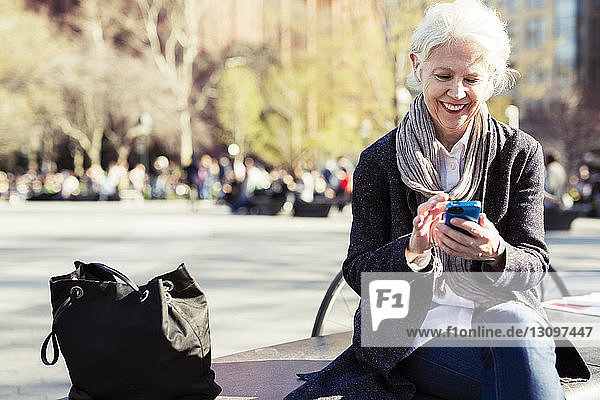 Glückliche ältere Frau mit Smartphone in der Stadt