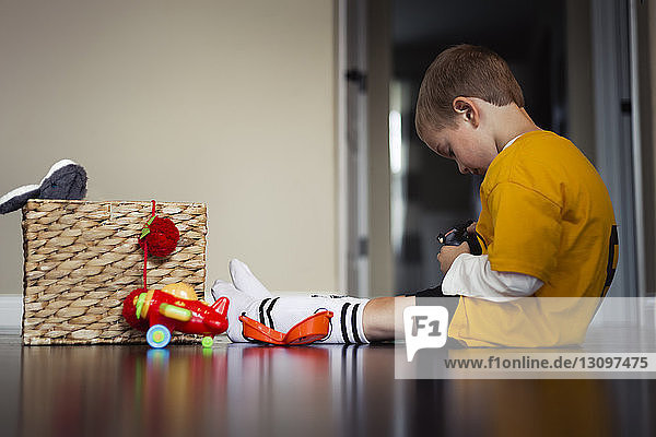 Seitenansicht eines Jungen  der mit Spielzeug spielt  während er zu Hause auf dem Boden sitzt