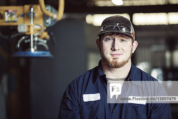 Portrait of confident blue collar worker wearing cap in steel factory