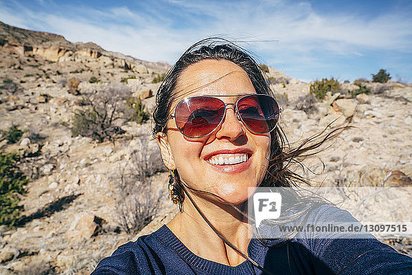 Porträt einer fröhlichen Frau mit Sonnenbrille in der Wüste