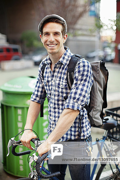 Porträt eines glücklichen Mannes mit Fahrrad auf der Straße
