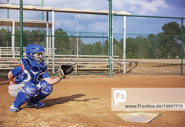 Baseball catcher crouching on field