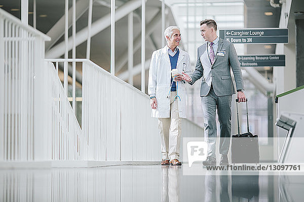 Male doctors talking while walking in hospital corridor