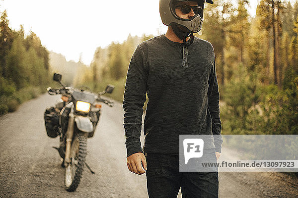 Biker wearing crash helmet while walking on dirt road
