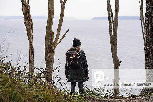 Rückansicht einer Frau mit Rucksack  die am Meer gegen den Himmel im Discovery Park steht