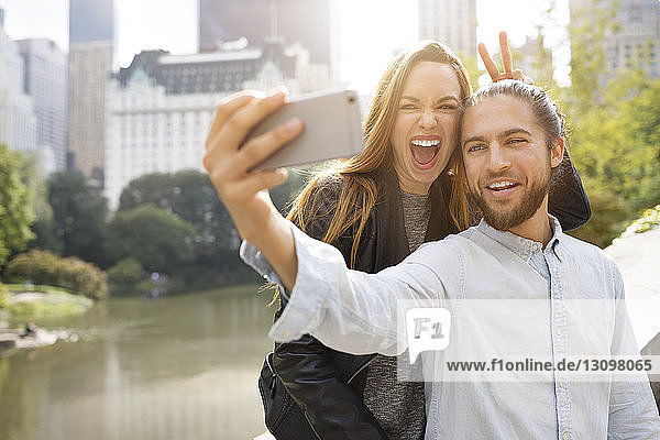 Cheerful couple taking selfie while leaning on retaining wall