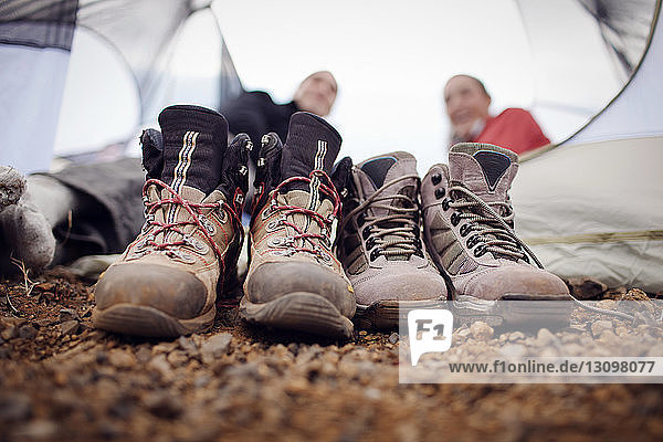 Close-up of dirty shoes with hikers relaxing in background