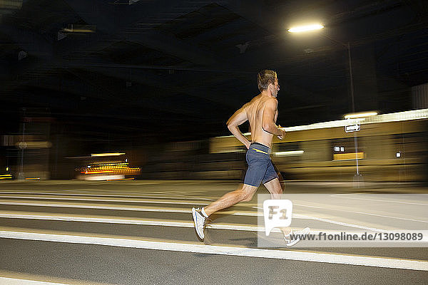 Athlet ohne Hemd läuft nachts auf der Strasse