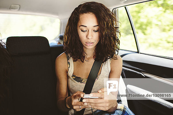 Woman using mobile phone while traveling in car