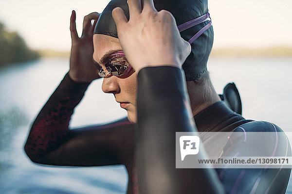 Female swimmer wearing swimming goggles at lakeshore