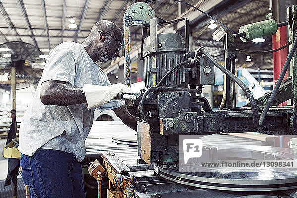 Seitenansicht eines Arbeiters  der eine Maschine zum Binden von Stahl in einer Fabrik benutzt