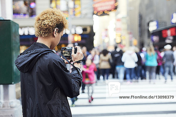 Rückansicht einer jungen Frau  die auf der Straße in der Stadt fotografiert