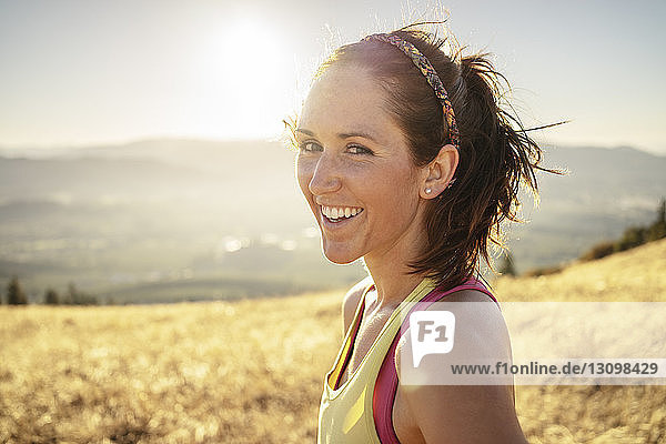 Portrait of smiling woman standing on mountain against clear sky during sunny day