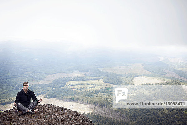 Hiker meditating on mountain
