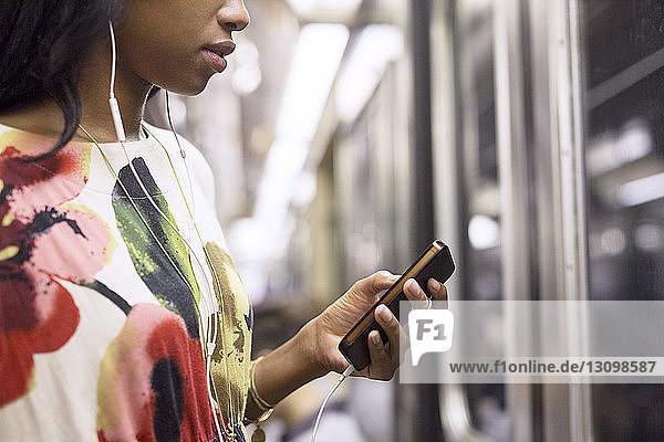 Frau  die während einer Zugfahrt Musik am Telefon hört