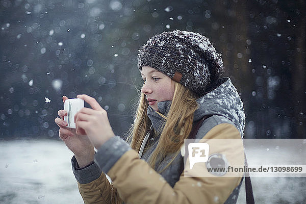 Frau fotografiert bei Schneefall per Handy