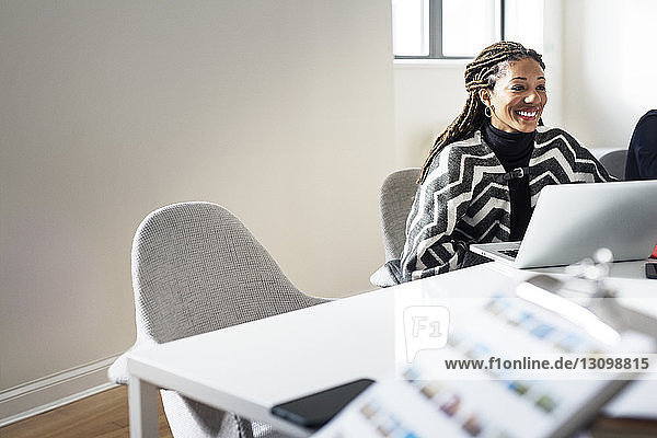 Smiling woman sitting by table during meeting in office