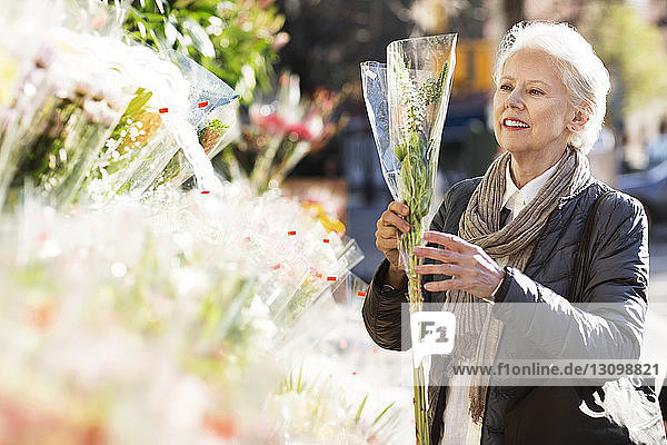 Ältere Frau kauft Blumen am Marktstand
