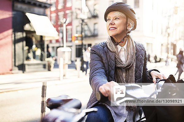 Nachdenkliche ältere Frau sitzt auf dem Fahrrad