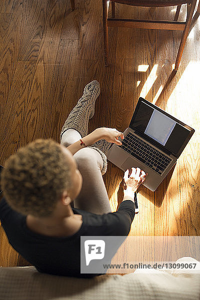Draufsicht einer Frau  die einen Laptop auf dem Hartholzboden im Schlafzimmer benutzt