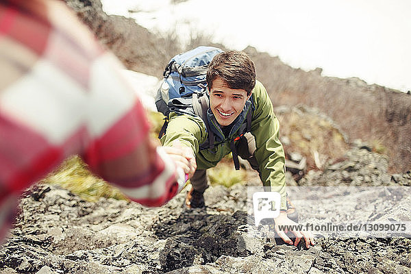 Ausgeschnittenes Bild einer Frau  die einem Freund beim Bergsteigen hilft