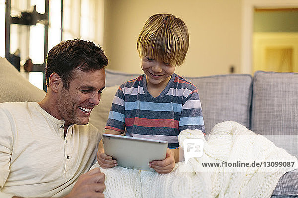 Vater mit Sohn benutzt Tablet-Computer  während er zu Hause sitzt