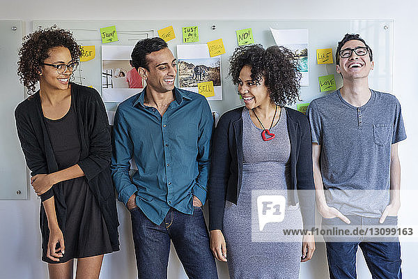 Glückliche multiethnische Geschäftsleute  die im Büro gegen die Tafel stehen
