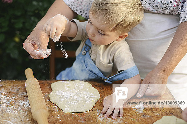 Mitschnitt einer Mutter mit ihrem Sohn  die auf einem Holztisch im Hof das Essen zubereitet