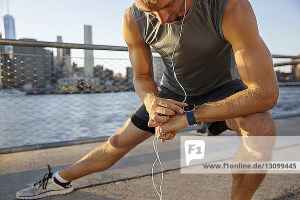 Midsection of athlete exercising on promenade by river