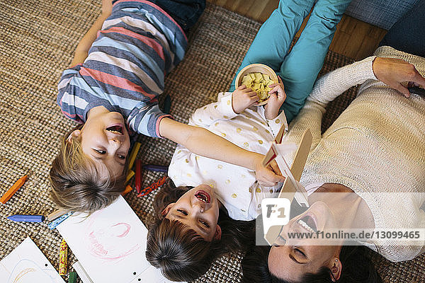Overhead view of playful children with mother lying on carpet at home