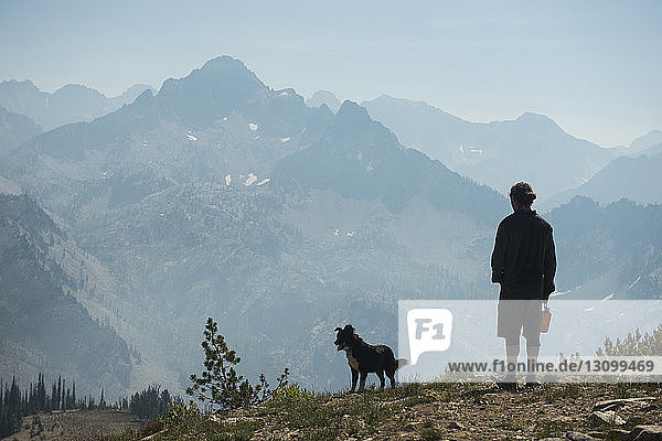 Rückansicht eines Mannes mit Hund auf einer Klippe in Sawtooth Range