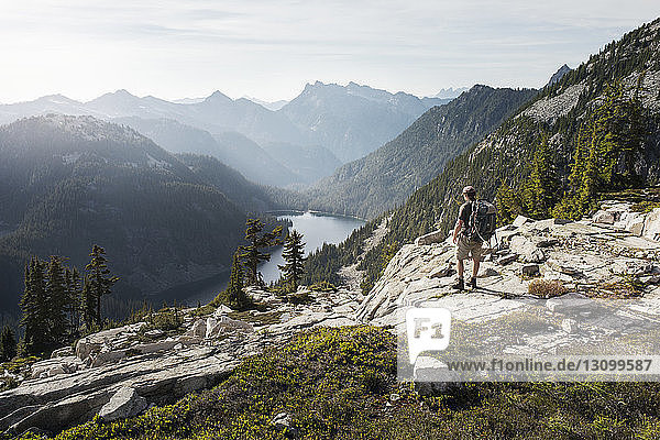 Rückansicht eines Mannes  der auf einer Klippe vor einer Bergkette steht
