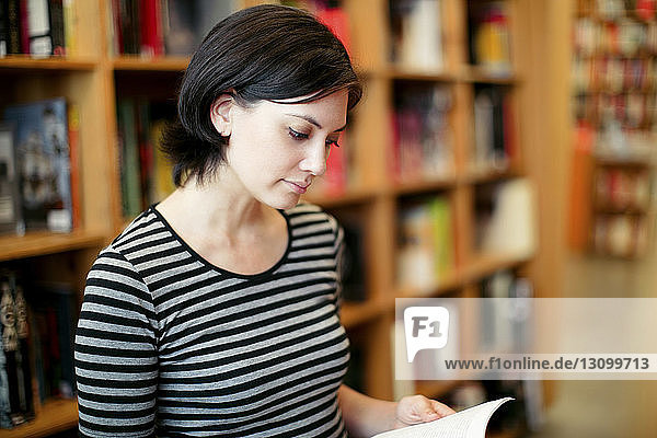 Junge Frau liest Buch in Bibliothek