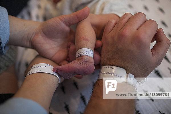 Beschnittenes Bild von Eltern und Neugeborenem mit Krankenhaus-Identifikationsarmbändern