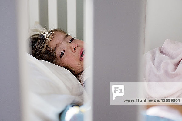 Portrait of baby girl crying while lying in crib at home
