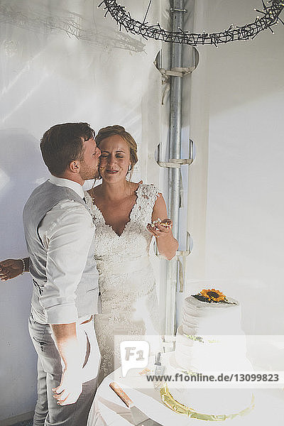 Bräutigam küsst Braut beim Hochzeitsempfang