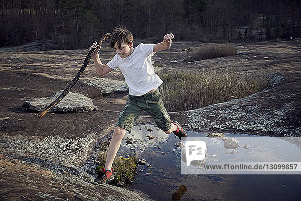 Boy jumping over puddle on Arabia Mountain