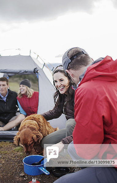Glückliche Freunde mit Hund auf dem Campingplatz