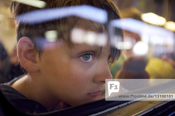 Junge schaut durch ein Fenster  während er im Zug unterwegs ist  durch Glas gesehen