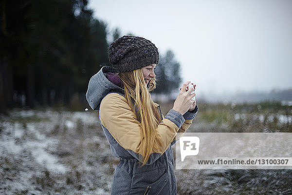 Frau fotografiert im Winter per Handy