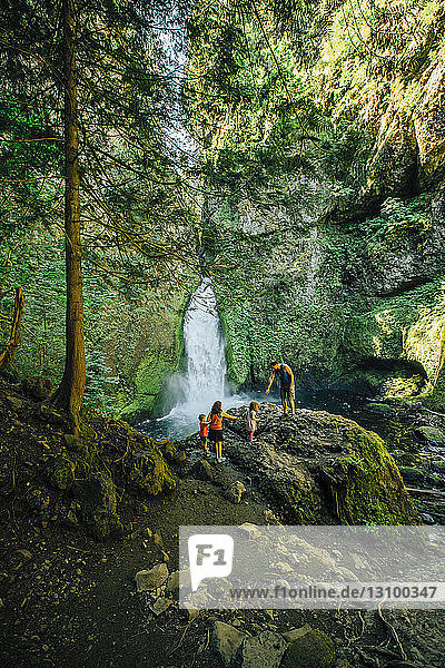 Familie auf Felsen gegen Wasserfall im Wald