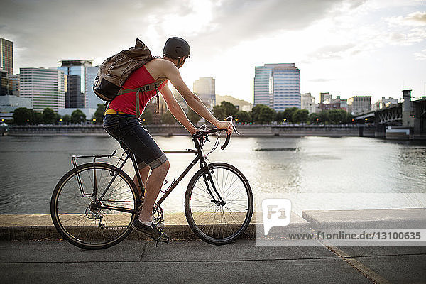 Sportler mit Rucksack beim Fahrradfahren auf der Straße am See in der Stadt