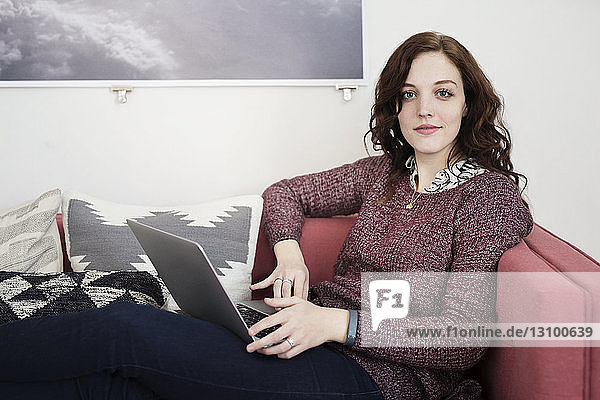 Portrait of businesswoman using laptop while sitting on sofa
