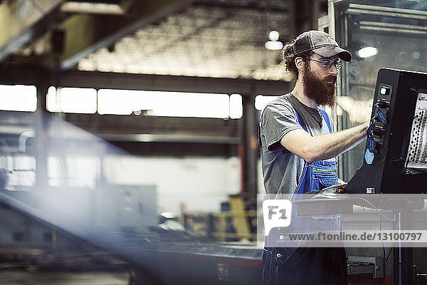 Manual worker wearing cap while using desktop computer in steel industry