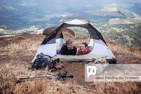 Happy hikers relaxing in tent on mountain