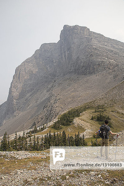 Hochwinkelaufnahme eines männlichen Wanderers  der auf einem Berg gegen den Himmel steht
