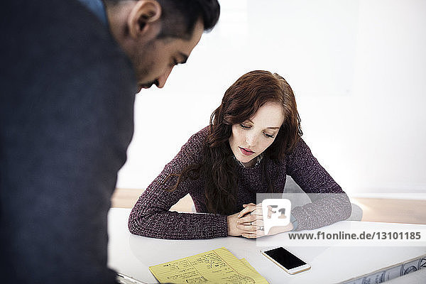 Businesswoman and male colleague checking document on table