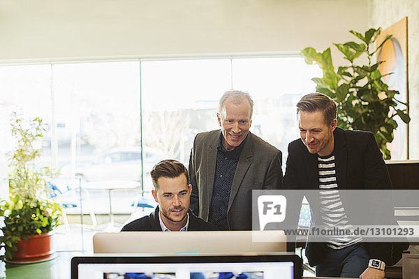 Männliche Kollegen mit Desktop-Computer am Schreibtisch im Büro